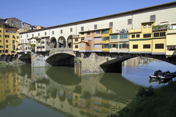 Fototapeta na wymiar Ponte Vecchio in Florence, Italy, reflecting in the river Arno on a sunny day