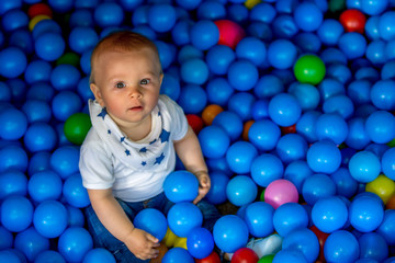 Fototapeta na wymiar Sweet little toddler child, baby boy, playing in colorful plastic balls
