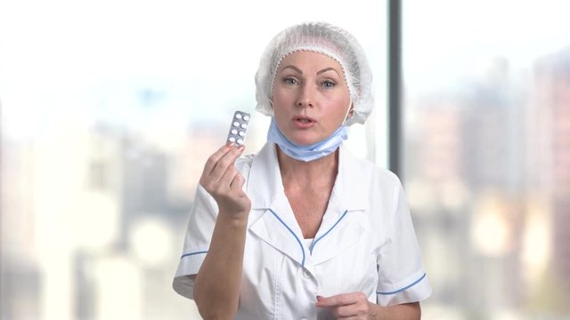 Female doctor nurse prescribing pills. Bright blurred background.
