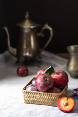 Obraz na płótnie Canvas Fresh plum. Autumn harvest. Red plums. Yellow plum. Fresh plums on a wooden surface. Fresh plums on wooden table background with napkin and vintage kettle and glass. Bronze ware.