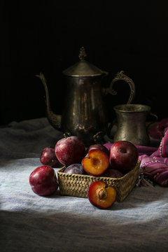 Fresh plum. Autumn harvest. Red plums. Yellow plum. Fresh plums on a wooden surface. Fresh plums on wooden table background with napkin and vintage kettle and glass. Bronze ware.
