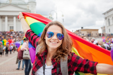 Smiling woman with rainbow flag in pride parade - obrazy, fototapety, plakaty