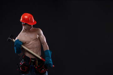 Handsome young topless construction worker with sledge hammer, studio shot, black background....