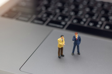 Miniature people: Businessman handshake to business success Online on laptop. Commitment, agreement, investment and partnership concept