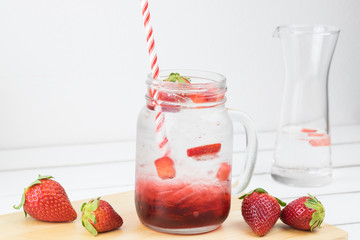 Fresh strawberry syrup and ice cube with soda for summer time on white wooden table background and strawberry fruits with copy space.