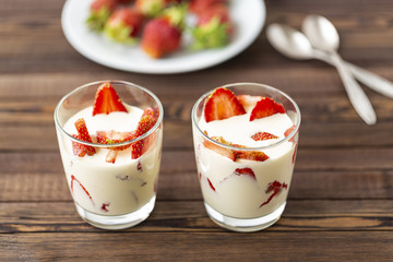 Closed up Yogurt in glass and strawberry on a wooden background. 