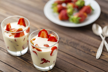 Closed up Yogurt in glass and strawberry on a wooden background. 