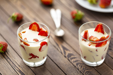 Closed up Yogurt in glass and strawberry on a wooden background. 