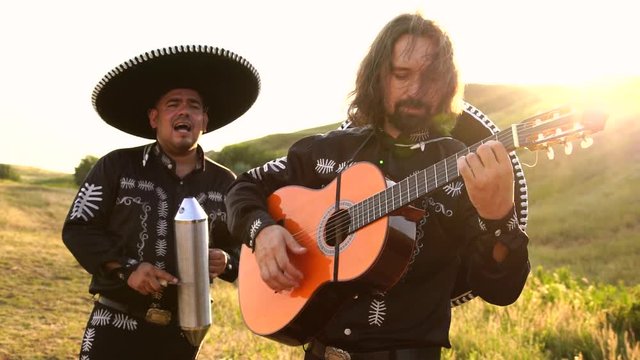 Mexican musicians mariachi play music at sunset. The rays of the sun give highlights. Slow motion