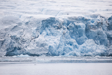 lengua de glaciar de tono azul que se adentra en el mar con una caída de hielo que se derrumba