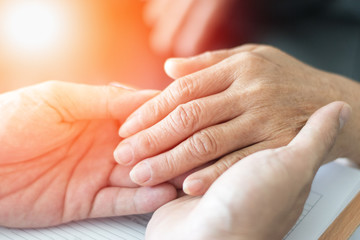 Caregiver, carer hand holding elder hand woman in hospice care. Philanthropy kindness to disabled concept.Public Service Recognition Week