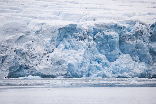 lengua de glaciar de tono azul que se adentra en el mar con una ca&iacute;da de hielo que se derrumba