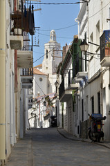 Fototapeta na wymiar Typical alley and Santa Maria church in the background of Cadaqués, commune on the Costa Brava at northeastern Catalonia in Spain