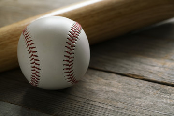 baseball and baseball bat on wooden table background, close up