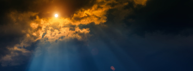 blurred background, sun and rays on a dark background of thunderclouds.