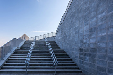 The modern urban stone stairway with the steel guardrails in the sunny day