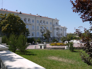 man sitting on a park bench in the shadow of a beautiful house standing behind him