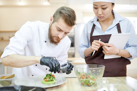 Portrait of handsome professional chef serving beautiful vegan dish while cooking in modern restaurant kitchen, copy space