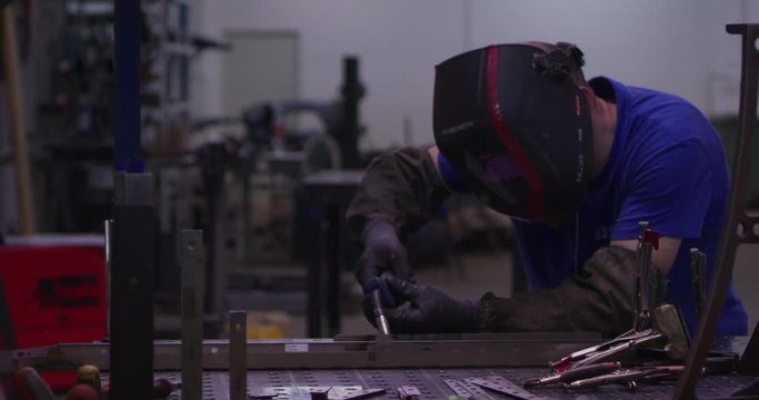 small business industrial worker at factory shop welding steel slow motion