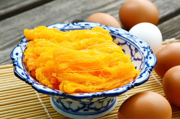 Golden egg strip is Thai desserts made from eggs with Thai style bowl on wooden background ( Thai name is Foi Thong).