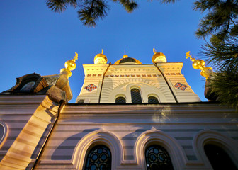 view from below upwards to the facade of the cathedral with gold-casting domes under the blue evening sky
