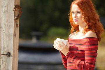 Slim caucasian woman holds cup of tea in her hands at mountain resort