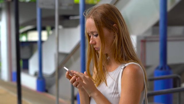 Young woman on a street lost in big city, trying to search through the map on her phone and book a taxi