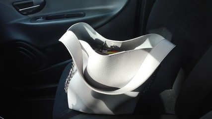 a white bag resting on a black seat of a car
