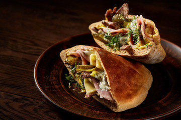 Pita stuffed with meat, cheese and sauce on wooden background, top view, selective focus.