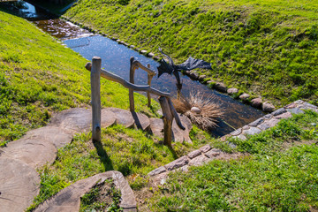 Round wooden steps with decorative ornaments, descending to a small river channel