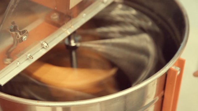 Two honey trays being spun inside a steel extractor removing honey from honeycombs.