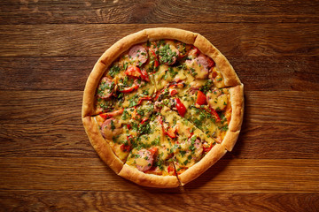 Freshly baked delicious pizza on rustic wooden background, top view, close-up, selective focus.