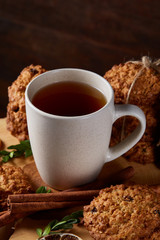 Christmas teatime with oatmeal, chocolate biscuits, and spices, on wooden background, close-up, selective focus.
