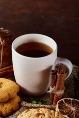 Christmas teatime with oatmeal, chocolate biscuits, and spices, on wooden background, close-up, selective focus.