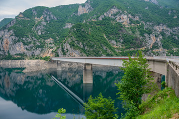 The big bridge is crossed by a picturesque mountain lake.