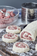 Making savoury cottage cheese pies with minced meat. Raw pies on wooden board, ingredients on background, vertical