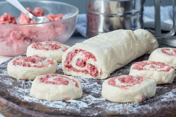 Making savoury cottage cheese pies with minced meat. Raw pies on wooden board, ingredients on background, horizontal