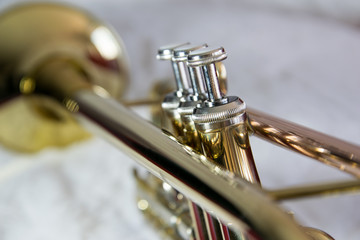 Trumpet, brass, focus on the valves rest of the trumpet blurry, positioned diagonally,  bell on the...