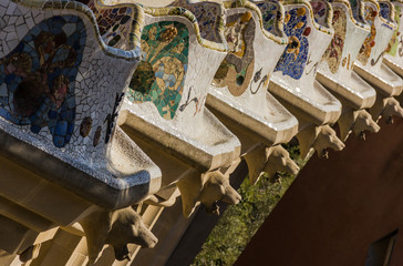 Angle perspective of mosaic terraces at Park Guell with creature heads in Barcelona. Tourist attraction, unique architecture concepts