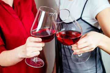 a glass of wine in the hands of two women closeup