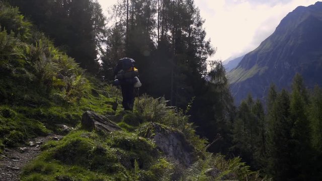 Two men are walking on a mountain terrain with a beautiful scenery.