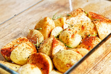 Potatoes in glass vessel and spicies on it (chili and rosemary) prepared to be baked or roasted