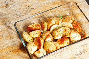 View on the glass vessel with raw potatoes inside (in the spices: rosemary, chili, paprika, salt and pepper) prepared to be baked