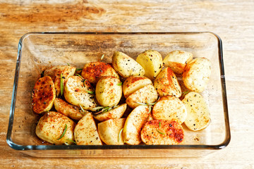 View on raw potatoes in spices (chili, paprika, salt, peper) in glass vessel in the kitchen on the prepared to be roasted