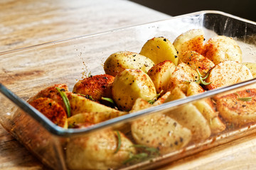 Delicious raw potatoes in spices (chili, paprika, salt, peper) in glass vessel on the wooden table prepared to be roasted