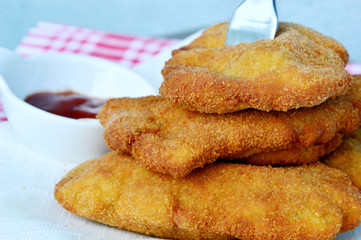 Wiener Schnitzel is popular in Austria or around Europe.
Wiener Schnitzel arranged in layers with fork and Ketchup, mayonnaise.