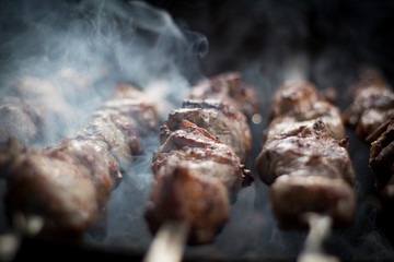 Barbecue outdoors on the grill.cooking meat on the street. street diner. picnic. family holiday. the meat on the shampoo. The heat from the grilled meat. the heat from the coals on the grill
