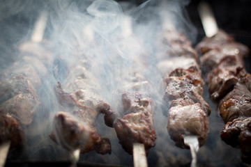 Barbecue outdoors on the grill.cooking meat on the street. street diner. picnic. family holiday. the meat on the shampoo. The heat from the grilled meat. the heat from the coals on the grill