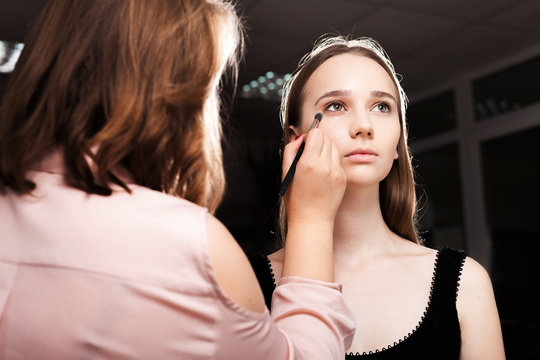 makeup artist dabbing the mixed foundation on a face of a young beautiful woman. concept of professional make up training