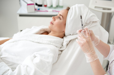 Side view smiling girl waiting for injection. Close up woman hand holding injector